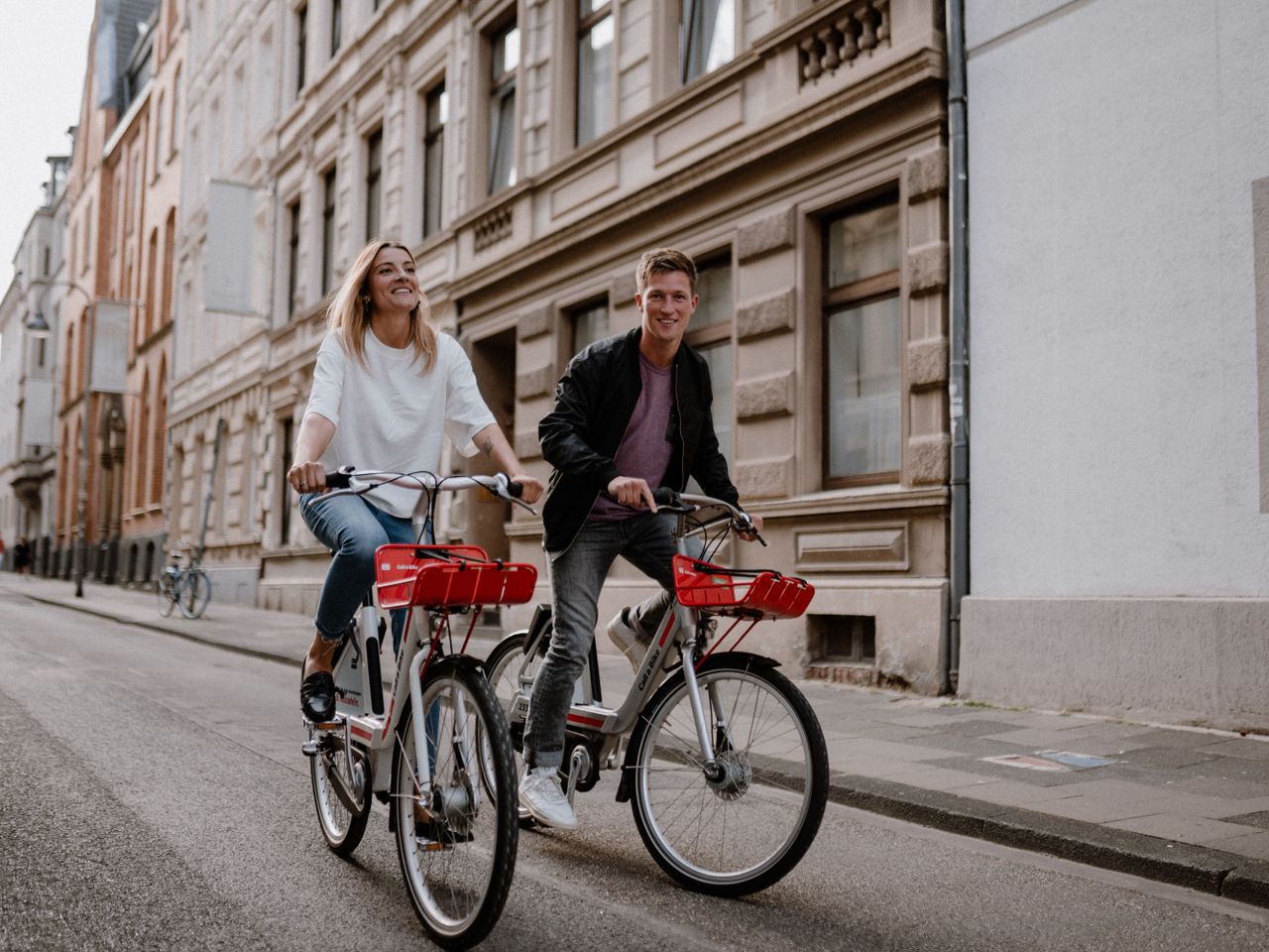 Woman and man ride their Call a Bike bicycles through the city center