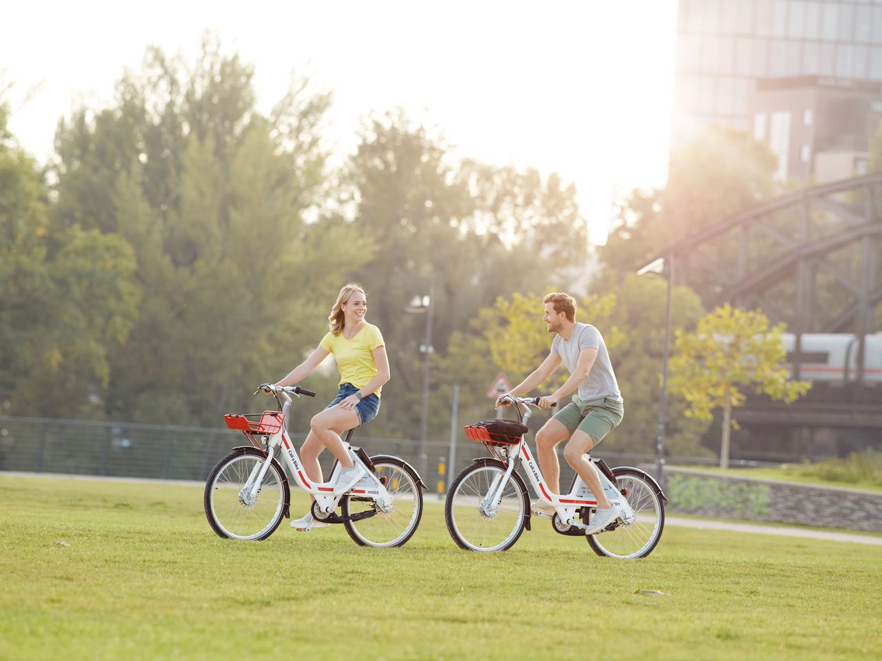 Frau und Mann fahren mit Call a Bike Fahrrädern durch einen Park